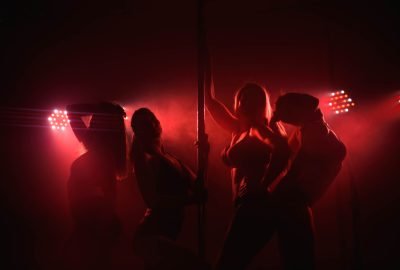 Dancers in dimmed red lights on stage in Helsinki striptease club