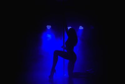 Girl dancing pole in blue lights in Sao Paulo striptease club