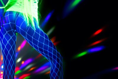 Dancer in Kiev striptease club illuminated by disco rainbow lights