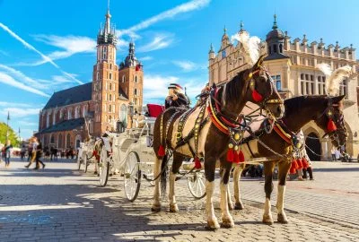 Carriage with horses to the background of the Saint Mary's Basilica and City Hall on the central market square Rynek Główny in Kraków