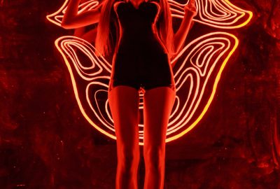 Beautiful girl in sexy pose illuminated by red neon light at nightclub in Kleinbasel